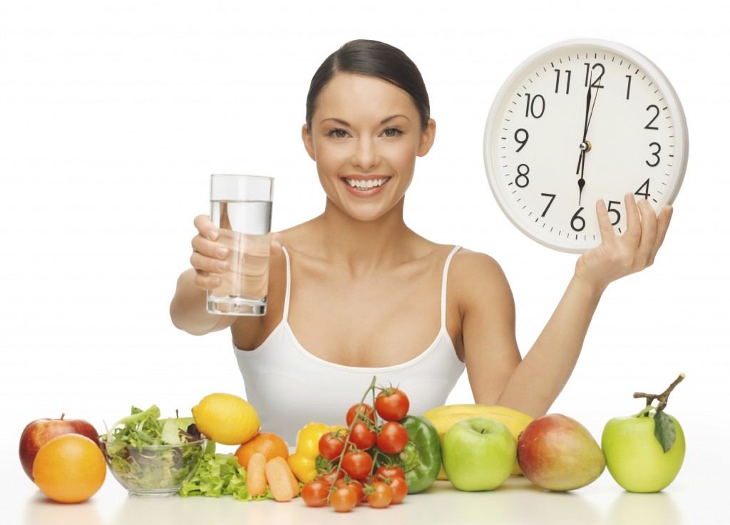 beautiful woman with healthy food water and clock